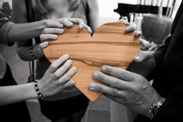 group of people holding a wooden heart